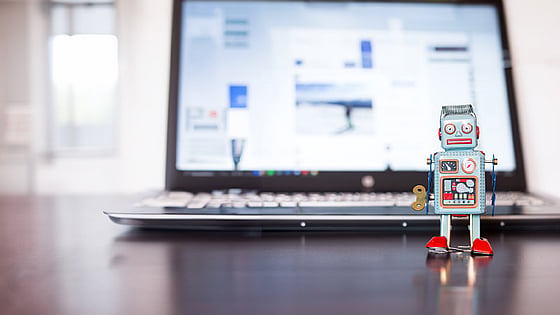 Laptop med en robotleksak ståendes framför