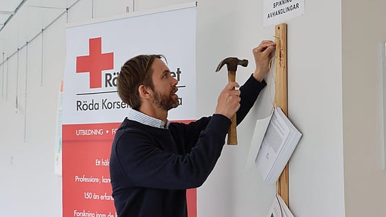 Doktoranden Andreas Malm spikade sin licentiatavhandling på Röda Korsets Högskolas vägg. Foto:RKH