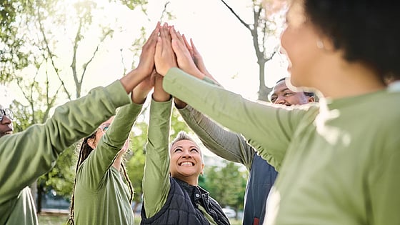 Personer som ger varandra highfive i skogen. Foto: Mostphotos.