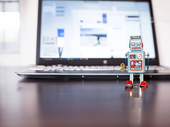 Laptop med en robotleksak ståendes framför