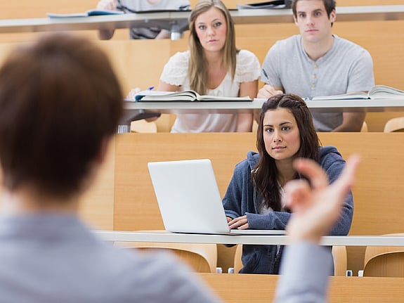 Bild av studenter som sitter och lyssnar på lärare.