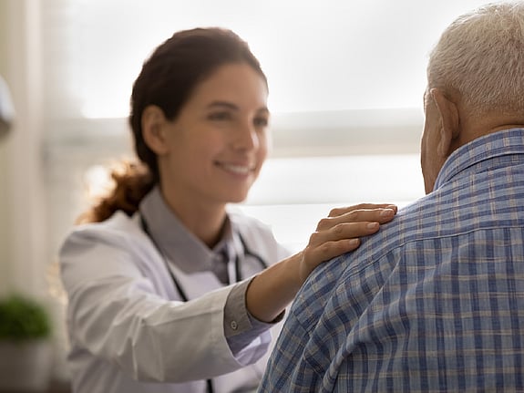 läkare håller handen på en patients axel. Foto: Mostphotos.