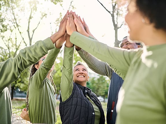 En grupp personer som highfivear i en skog. Foto: Mostphotos.