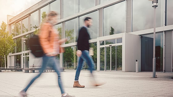 Två personer som går mot en byggnad