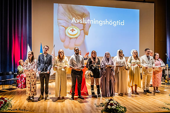 Studenter vid Röda Korsets Högskola står på scen under avslutningshögtiden. Foto: Jenny Frejing